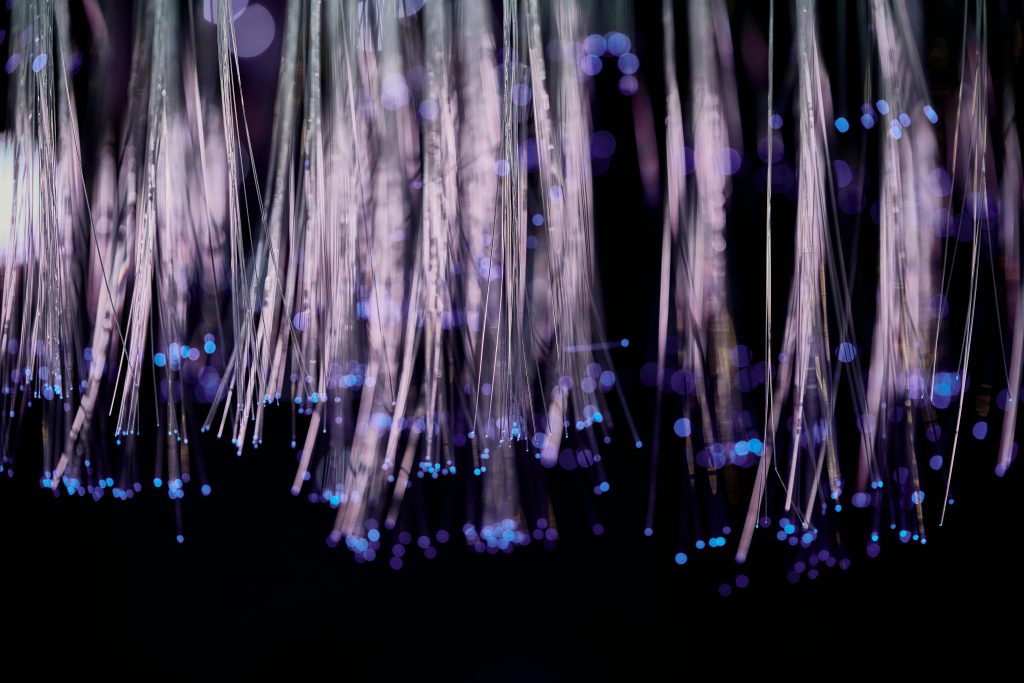Close-up of glowing fiber optic lights with a purple and blue bokeh effect.